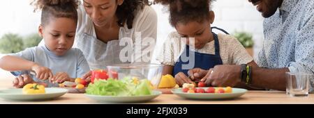 Glückliche afroamerikanische Eltern lehren Geschwister Kinder zu kochen Stockfoto