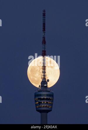 Stuttgart, Deutschland. April 2021. Der Vollmond steigt hinter dem Stuttgarter Fernsehturm auf. Am 27. April 2021 wird es einen sogenannten "Supermond" geben. Dann ist der Abstand zwischen Mond und Erde kleiner als üblich. Quelle: Marijan Murat/dpa/Alamy Live News Stockfoto