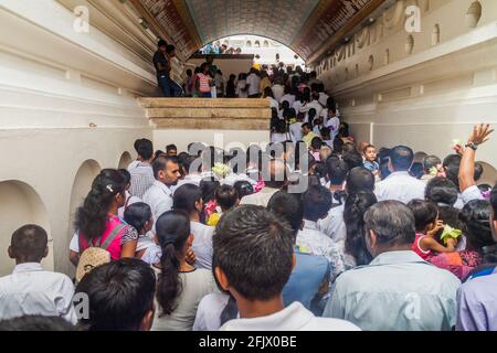 KANDY, SRI LANKA - 19. JULI 2016: Weiß gekleidete buddhistische Anhänger warten während der Poya-Zeit in einer Schlange am Eingang zum Tempel der Heiligen Zahnreliquie Stockfoto