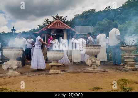 KANDY, SRI LANKA - 19. JULI 2016: Weiß bekleidete buddhistische Anhänger zünden während des Poya-Vollmondholids Räucherstäbchen am Tempel der Heiligen Zahnreliquie an Stockfoto