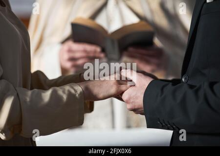 Nahaufnahme eines jungen Paares, das die Hände hält und heiratet Die Kirche Stockfoto