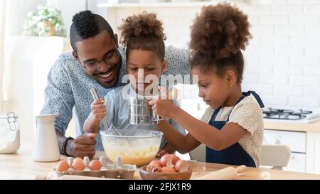 Glücklich Vater lehrt zwei niedliche Vorschulkinder zu backen Stockfoto