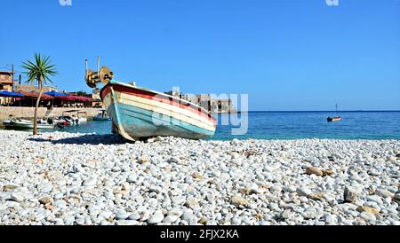 Meereslandschaft mit einem traditionellen griechischen Fischerboot an der Kiesküste von Gerolimenas in Lakonia Peloponnes, Griechenland. Stockfoto