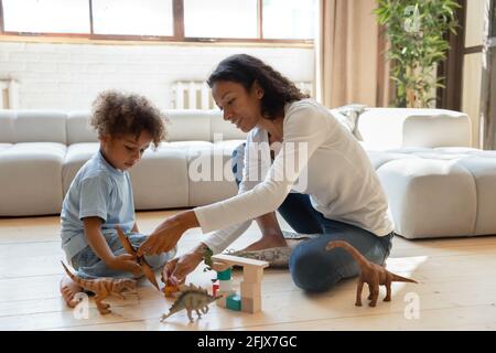 Afroamerikanische Mutter und kleiner Kleinkind Sohn spielen mit Dinosauriern Stockfoto