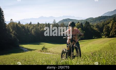 Frau, die an einem schönen Tag mit dem Mountainbike in der Natur bergauf geht. Stockfoto