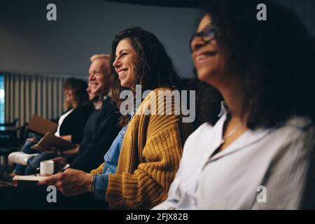 Gruppe von Geschäftsleuten, die am Seminar sitzen. Menschen, die während einer Tagung lächelnd im Publikum sitzen. Stockfoto