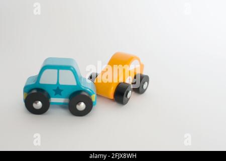 Autounfall von zwei Spielzeugautos aus Holz, blau und gelb. Weißer Hintergrund Stockfoto