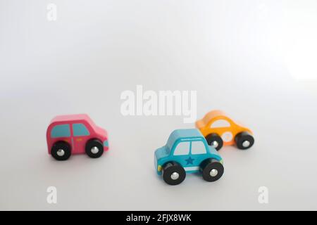 Drei kleine Spielzeugautos rosa, gelb und blau. Weißer Hintergrund Stockfoto
