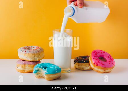 Süße Donuts mit Mann Hand Gießen Milch Stockfoto