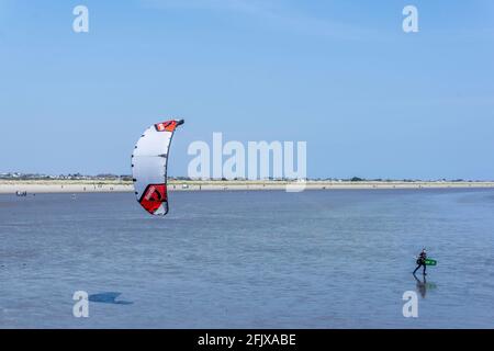 Kitesurfen. Ein eineineinmunter Kite-Surfer am Dollymount Strand in Dublin, Irland, der sich in Richtung Wasser bewegt. Stockfoto