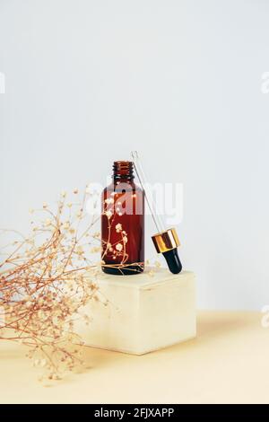 Natürliches ätherisches Öl oder Serum in brauner Glasflasche mit Pipette auf einem Holzpodium. Alternative Medizin, Schönheit Hautpflege-Produkt. Speicherplatz kopieren Stockfoto