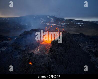 Brennende Lava, die im rauen Vulkankrater spritzt Stockfoto