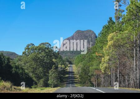 Eine Straße durch die Glass Mountains von Queensland Australia That Es sieht so aus, als würde es direkt auf ein antikes Alter zusteuern Vulkanischer Berg durch tr Stockfoto