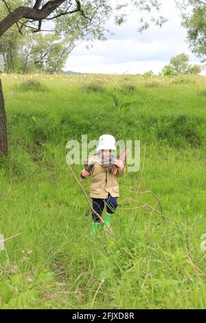 Ein 3-jähriges Kind spaziert auf einer grünen Wiese Stockfoto