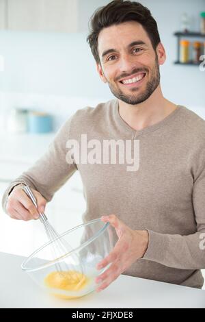 Mann, der Eier in der Schüssel hastert Stockfoto