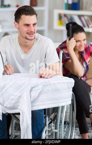 gut aussehend behinderten Mann im Rollstuhl vor dem Fernseher mit seiner Freundin Stockfoto