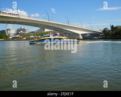 Brisbane Australien um 2015-CityCat unter Fußgängerbrücke mit dem Rad von Brisbane im Hintergrund Stockfoto