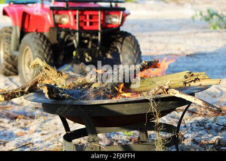 Selektiver Fokus auf Lagerfeuer mit atv im Hintergrund auf einem Campingplatz. Stockfoto