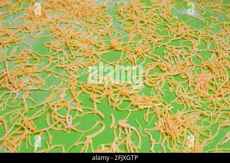 Hausgemachte Nudeln auf einem grünen Tisch machen Streifen während des Trocknungsprozesses von glutenfreiem Weizenmehl aus der Nähe, niemand Stockfoto