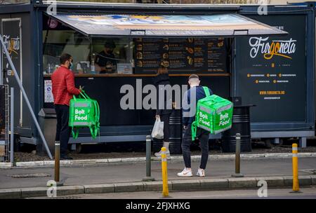 Bukarest, Rumänien - 05. April 2021: Bolt Food Delivery Kuriere stehen in einem Fast-Food-Restaurant auf der Straße nach der Regel der sozialen Distanzierung während Stockfoto