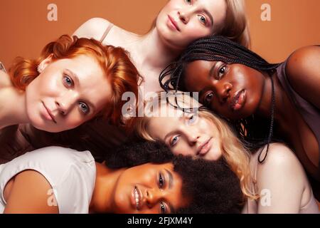 Junge hübsche kaukasische, afro, skandinavische Frau posiert fröhlich zusammen auf braunem Hintergrund, Lifestyle diverse Nationalität Menschen Konzept Stockfoto