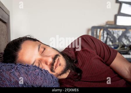 Junger latein schläft zu Hause auf dem Bett. Mann, der zu Hause ein Nickerchen macht. Stockfoto