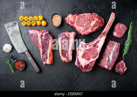 Verschiedene Schnitte von marmoriertem Rindfleisch und trocken gereiften Steaks Set, Tomahawk, t bone, Club Steak, Rib Eye und Filet Schnitte, auf schwarzem Stein Hintergrund, oben V Stockfoto