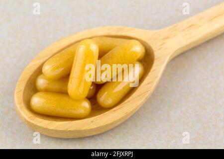 Closeup Konzentriertes Gelée Royale in Weichgel-Kapseln in Holzlöffel, Premium-Bienenprodukte als Nahrungsergänzungsmittel verwendet Stockfoto