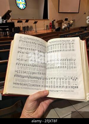 Person singen Hymne Gottesdienst Lied in einer Kirche, hält ein spanisches Hymnbuch, christliches Konzept Stockfoto