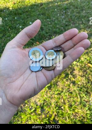Eine Person, die ein paar mexikanische Münzen hält, wechseln. Mexikanische Währung. Stockfoto