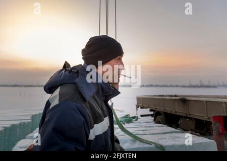 Porträt eines Arbeiters in einer blauen Jacke mit einem Haube und eine Zigarette im Mund Stockfoto