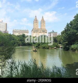 Blick auf den See im Central Park mit Blick auf das San Remo Gebäude. Die Menschen reiten Gondeln und Kanufahren. Stockfoto