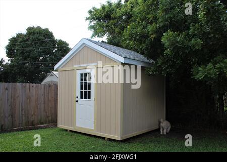 DIY Projekt Modell Hinterhof Werkzeugschuppen mit einem Hund draußen in einem Hof. Viele Bäume umgeben den Schuppen. Stockfoto