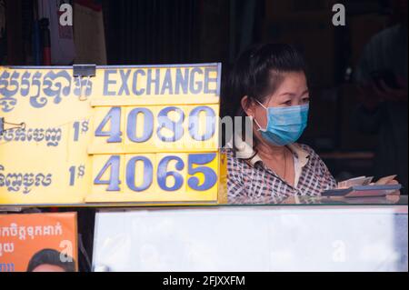 Eine kambodschanische Frau, die eine schützende Gesichtsmaske/Abdeckung an einem Geldwechselstand trägt, zählt Khmer riel während der Coronavirus-Pandemie auf. Kandal Market, Phnom Penh, Kambodscha. März 2020. © Kraig Lieb Stockfoto