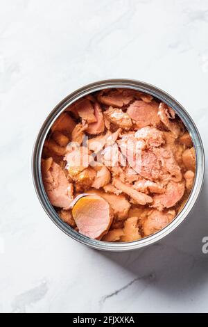 Offene Dose mit Thunfisch, Draufsicht, weißer Marmorhintergrund. Konzept für Konserven. Stockfoto