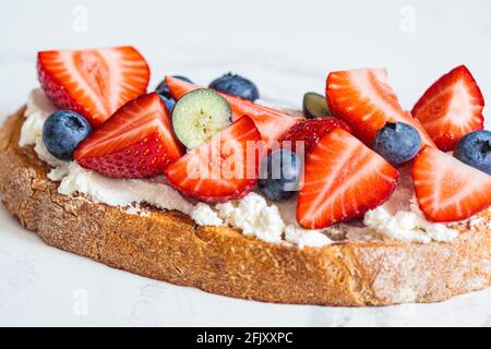 Toast mit Frischkäse, Erdbeeren, Heidelbeeren und Ahornsirup. Sommerliches Food-Konzept. Stockfoto