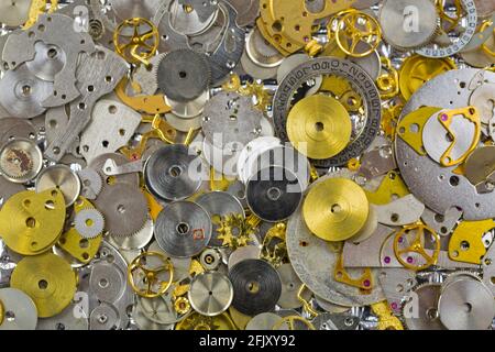 Textur der Uhrenteile in silbergoldenen Farben. Kleine Stücke von Zahnrädern, um Charme oder DIY Schmuck-Projekt zu machen Stockfoto