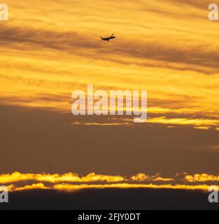 Wimbledon, London, Großbritannien. 27. April 2021. Eine frühe Ankunft am Flughafen London Heathrow beginnt den Abstieg vor einem farbenfrohen Hintergrund von frühen Wolken bei Sonnenaufgang. Quelle: Malcolm Park/Alamy Live News. Stockfoto