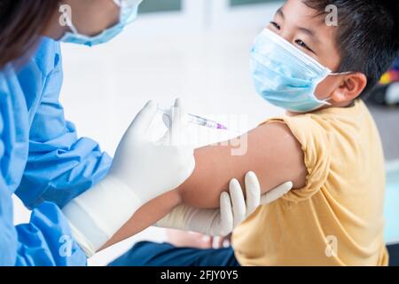 Arzt, der eine Impfung in der Schulter des Patienten Junge oder Kind Person und glücklich, Injektion am Arm, Coronavirus, covid-19 Impfstoffkrankheit Vorbereitung Stockfoto