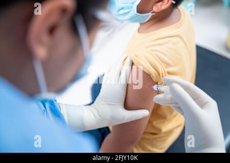 Nahaufnahme Arzt, der eine Impfung in der Schulter des Patienten Jungen oder Kind Person, Coronavirus, covid-19-Impfstoff-Krankheit Vorbereitung für den menschlichen klinischen Stockfoto