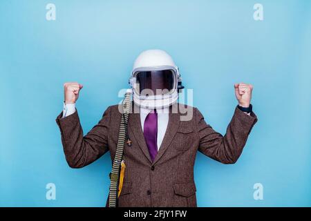 Geschäftsmann mit Astronautenhelm, der die beschwor raffenden Fäuste feiert Stockfoto