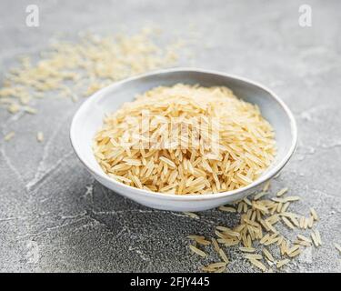 Ungekoter Basmati-Reis auf grauem Betongrund Stockfoto