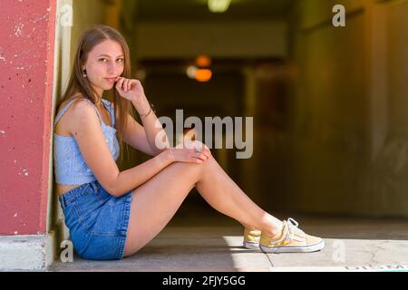 Junge Frau saß auf dem Boden in der Nähe eines Fußgängertunnels Stockfoto