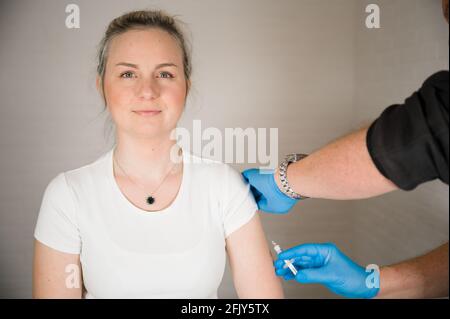 Arzt injiziert Covid-Impfstoff in einen Patientenarm: Heilung der Corona-Pandemie durch Massenimpfung Stockfoto