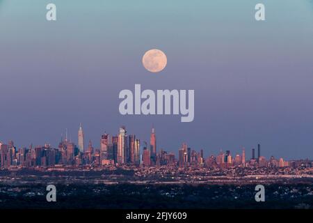 New York, USA. April 2021. Das Foto, das am 26. April 2021 in West Orange von New Jersey aufgenommen wurde, zeigt einen Supermond, der über der Skyline von Manhattan in New York, USA, aufsteigt. Quelle: Wang Ying/Xinhua/Alamy Live News Stockfoto