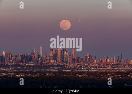 New York, USA. April 2021. Das Foto, das am 26. April 2021 in West Orange von New Jersey aufgenommen wurde, zeigt einen Supermond, der über der Skyline von Manhattan in New York, USA, aufsteigt. Quelle: Wang Ying/Xinhua/Alamy Live News Stockfoto