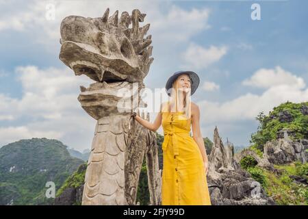 Frau Tourist auf dem Hintergrund der erstaunlichen riesigen Drachenstatue auf Kalkstein Berggipfel in der Nähe Hang Mua Aussichtspunkt am nebligen Morgen. Beliebter Tourist Stockfoto