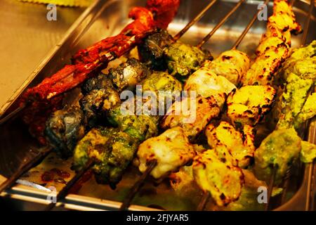 Mehrfarbige und aromatisierte indische Tandoori-Kebabs oder Tikka in einem Spieß-, Lehmofen-Lebensmittelprodukt Stockfoto