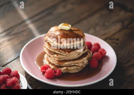 Haferpfannkuchen mit Butter, Himbeeren und Ahornsirup auf einem Holztisch Hintergrund. Essen am Morgen Stockfoto