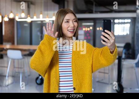Porträt einer asiatisch lächelnden Geschäftsfrau, die mit einem Videoanruf steht Smartphone Stockfoto